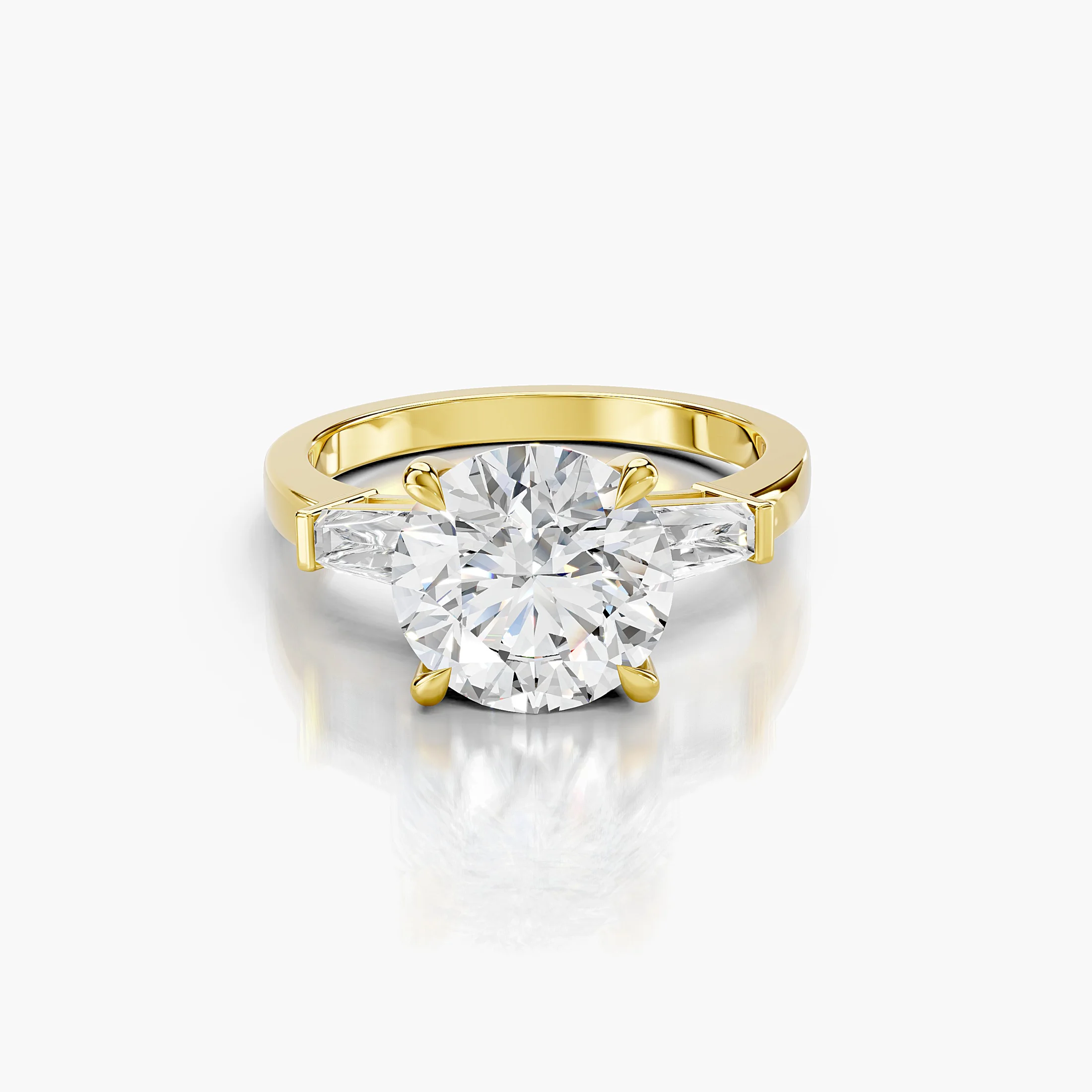 Three-stone engagement ring featuring a round center diamond flanked by tapered baguette diamonds.