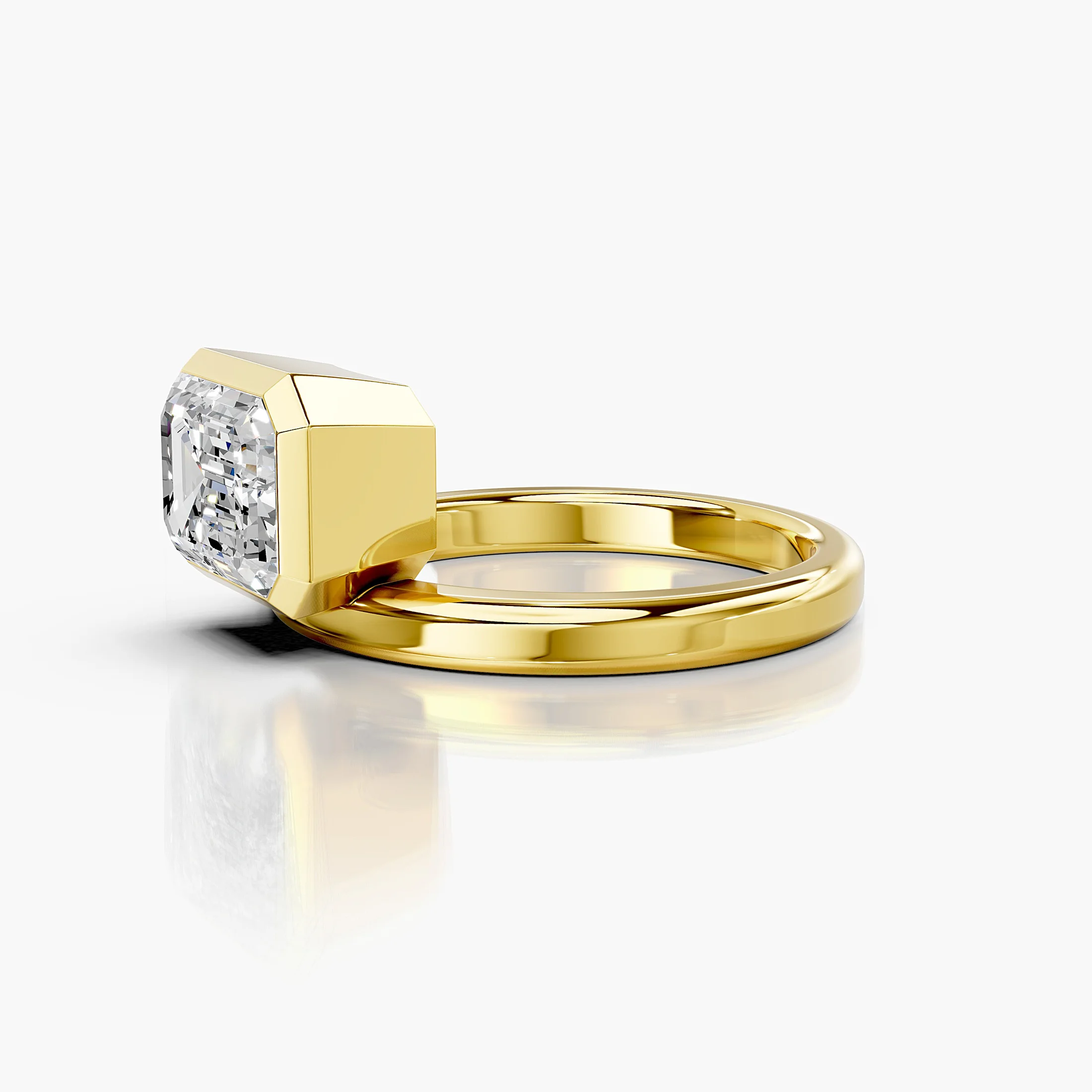 Emerald-cut diamond solitaire ring set in a bold bezel on a wide polished band.