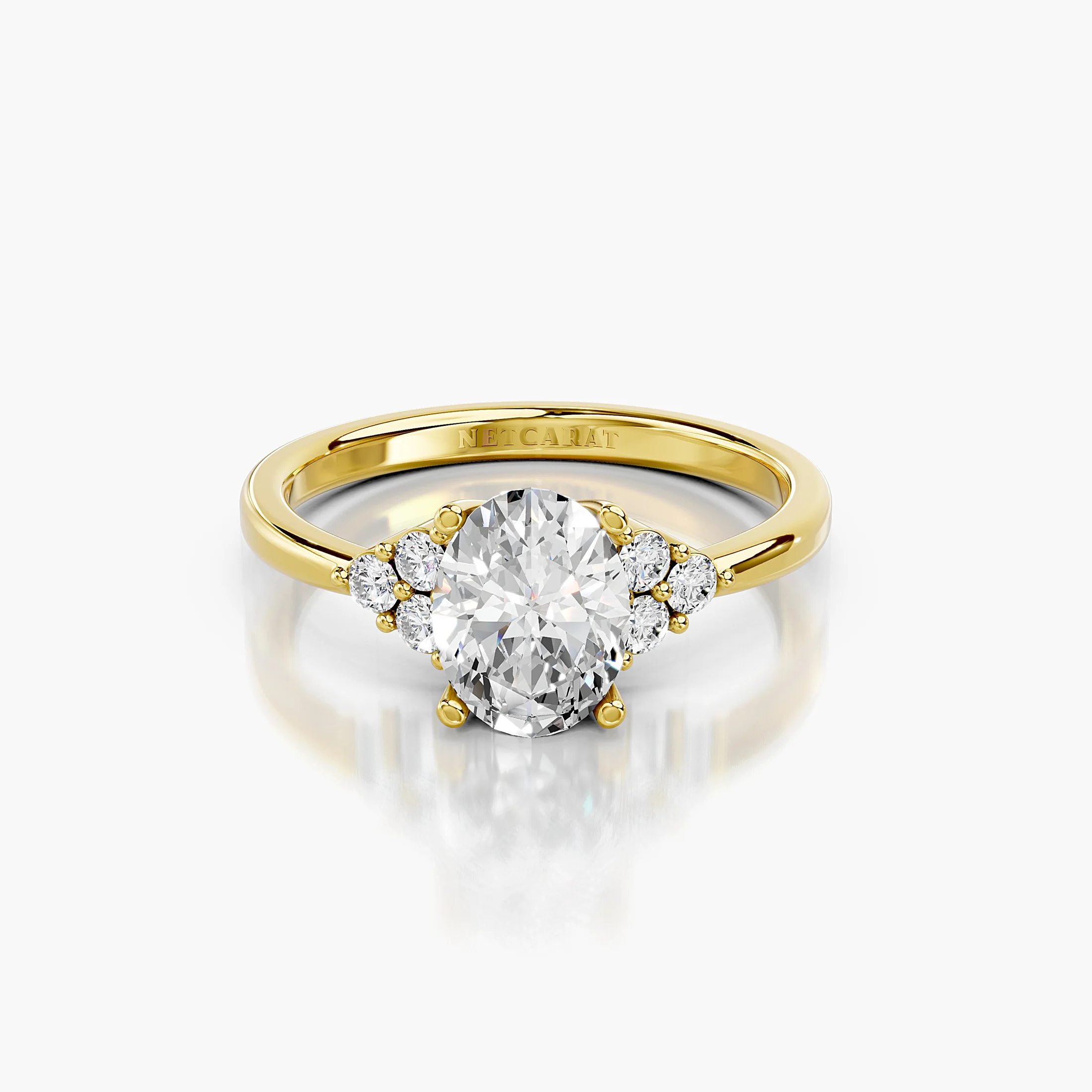 Oval four-prong engagement ring with three clustered round side stones on each shoulder and a polished tapered band.