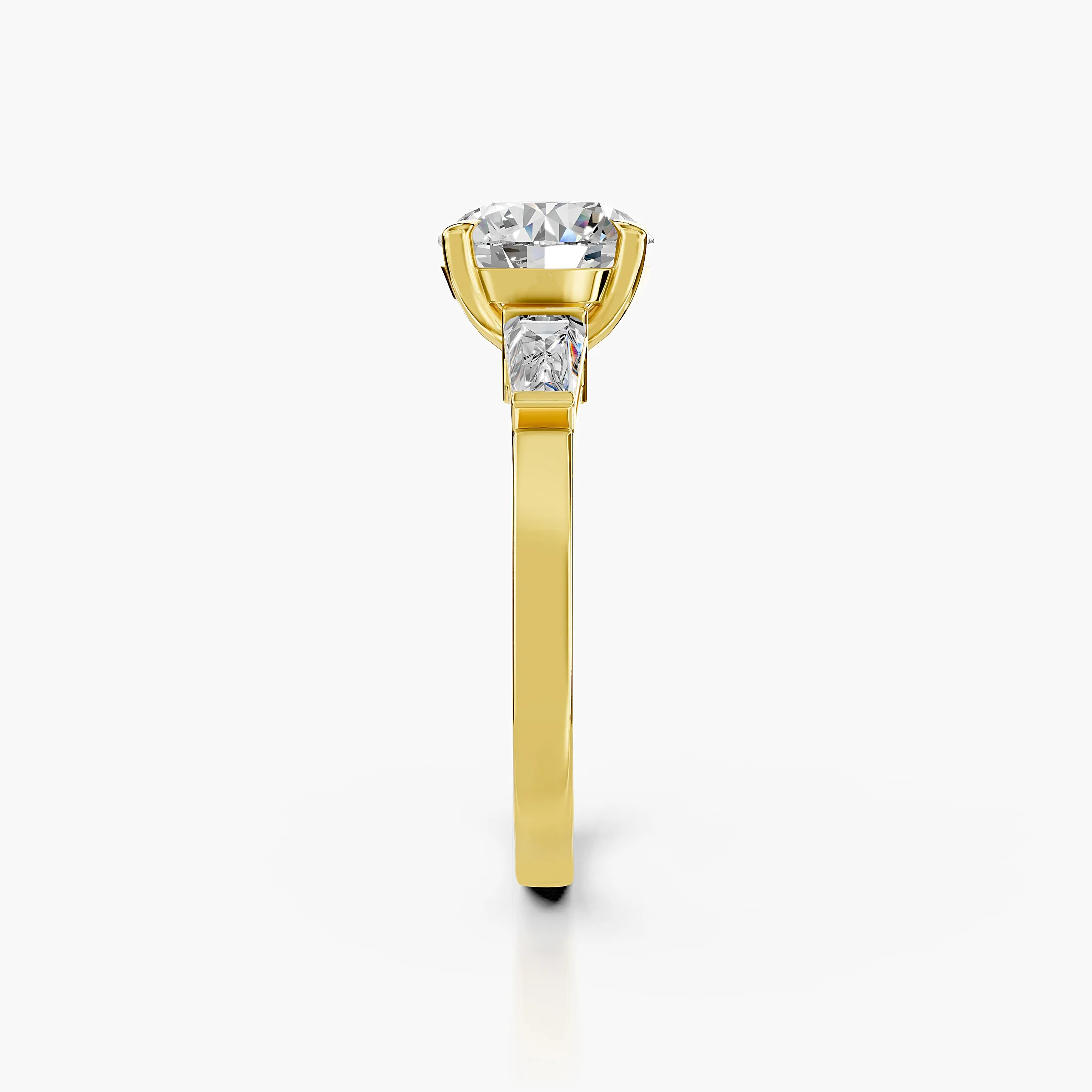 Three-stone engagement ring featuring a round center diamond flanked by tapered baguette diamonds.