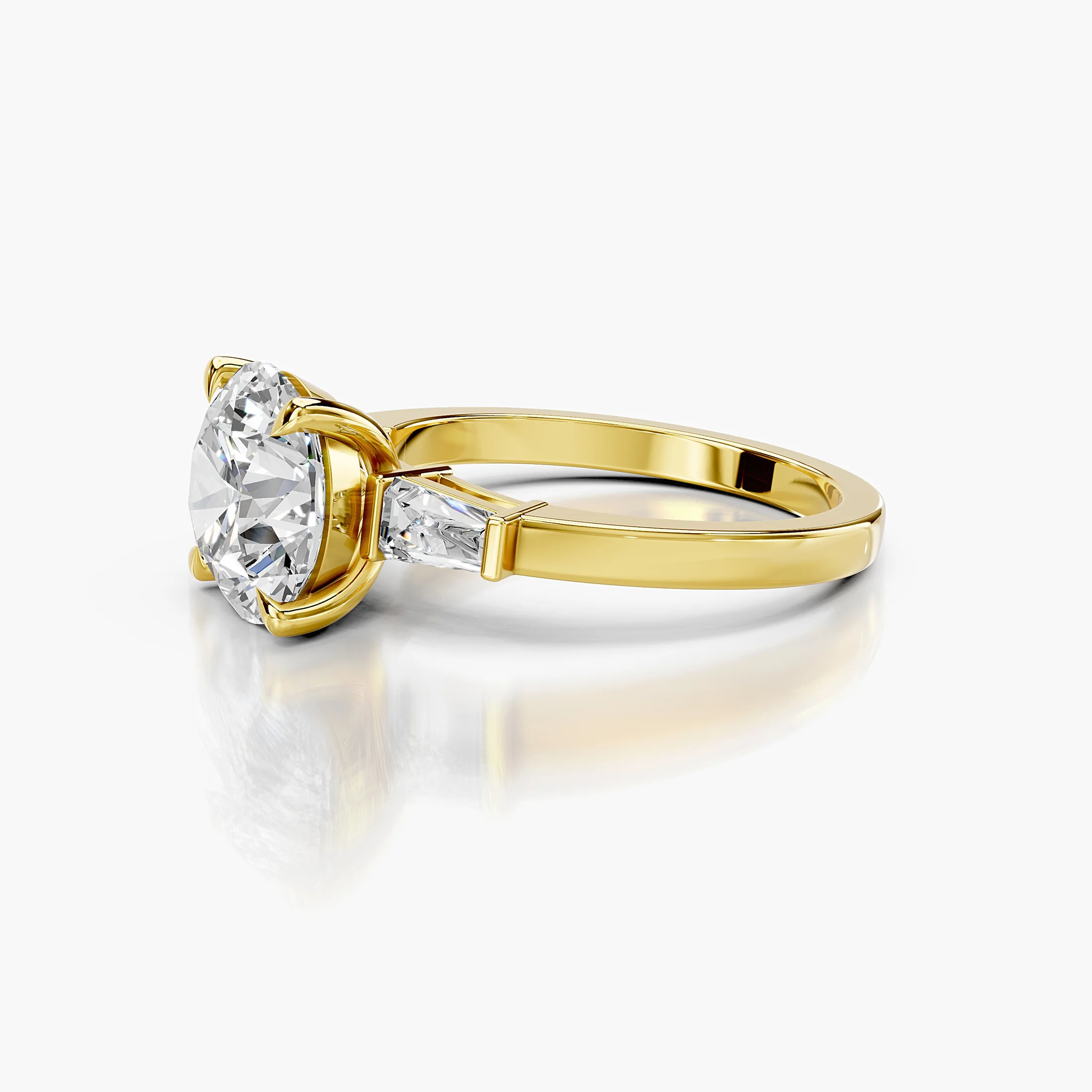 Three-stone engagement ring featuring a round center diamond flanked by tapered baguette diamonds.