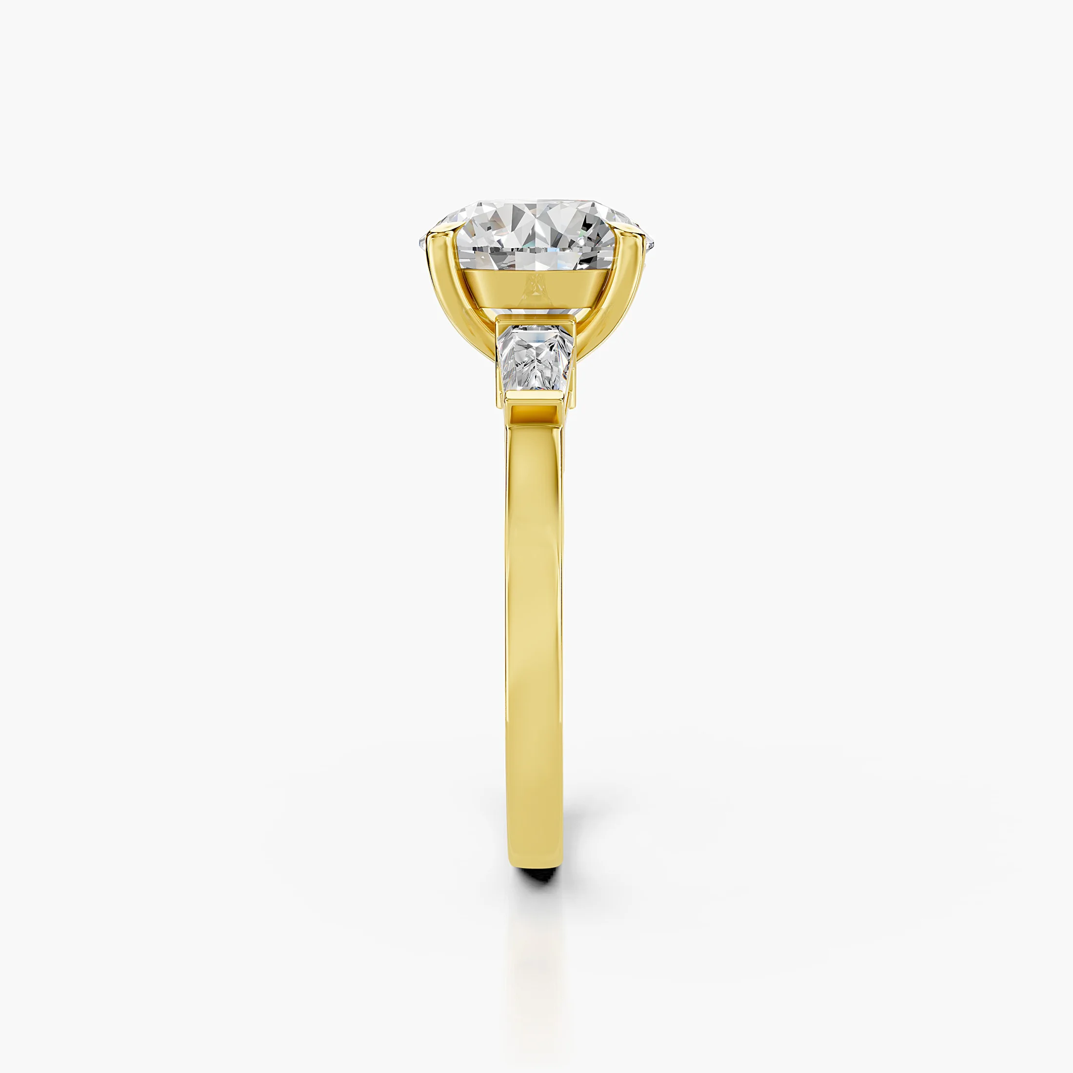 Three-stone engagement ring featuring a round center diamond flanked by tapered baguette diamonds.