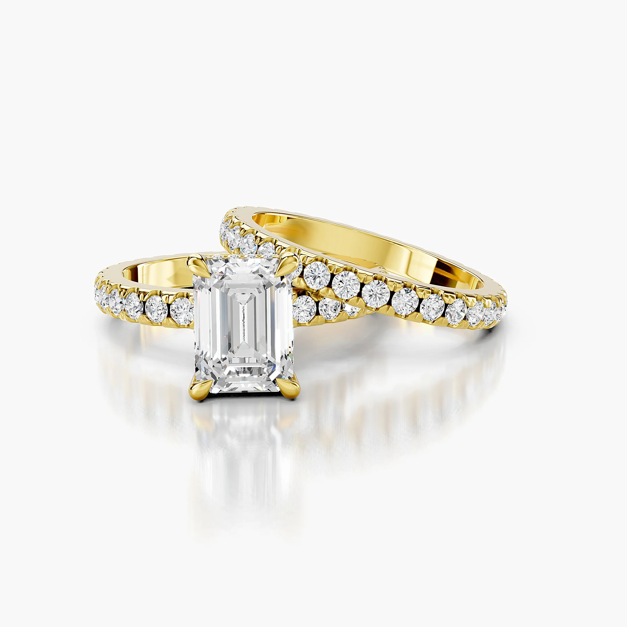 Emerald center engagement ring with hidden halo, round side stones, and straight coordinating diamond wedding band